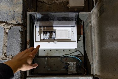 Bodrum duvarındaki eski elektrik sigorta kutusu, eski bir evde elektrik kesintisi, elektrik kesintisi, bozuk elektrik sistemi.