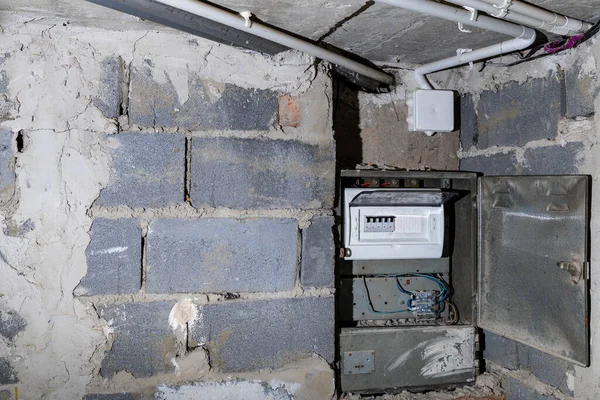Bodrum duvarındaki eski elektrik sigorta kutusu, eski bir evde elektrik kesintisi, elektrik kesintisi, bozuk elektrik sistemi.