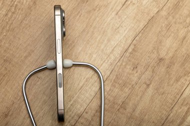 Hasarlı bir cep telefonu ahşap servis masasına yerleştirilmiş, steteskop kulaklıkları, telefon arızası aramak, telefonu kendin tamir etmeye çalışmak, cep telefonu servisi.