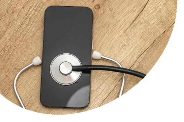 Siyah ekranlı hasarlı bir cep telefonu ahşap servis masasına yerleştiriliyor, steteskop kulaklıklarıyla, telefonu kendin tamir etmeye çalışırken, cep telefonu servisi...