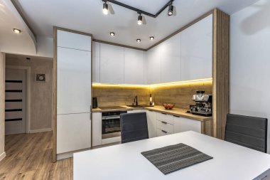 Modern mutfak mobilyaları, beyaz parlak ön kaplamalı mobilyalar, mutfaklı modern oturma odası, apartman yenilenmesi, fırınlı fonksiyonel mutfak mobilyası, indüksiyon hob, kahve makinesi, mutfakta siyah lavabo.