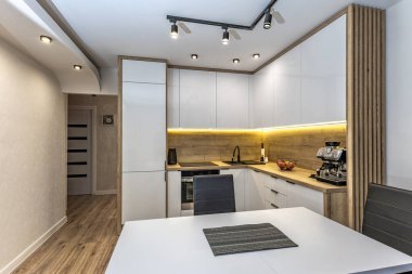 Modern mutfak mobilyaları, beyaz parlak ön kaplamalı mobilyalar, mutfaklı modern oturma odası, apartman yenilenmesi, fırınlı fonksiyonel mutfak mobilyası, indüksiyon hob, kahve makinesi, mutfakta siyah lavabo.