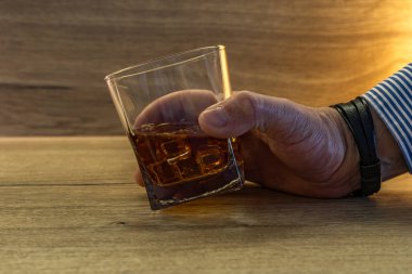 Zarif bir tişört giymiş bir şoför bir bardak viskiyi ahşap tezgahtan buzla alır, araba anahtarlarını bir barın yanındaki bir barın üzerine koyar, bir araba sürücüsü tarafından alkol tüketilir.