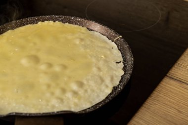Krep hamurunun yakın plan çekimi tavaya dökülmesi indüksiyon hobında kızartılan krepler evdeki mutfakta kızartılan altın krep hamuru, gerçek fotoğraf.