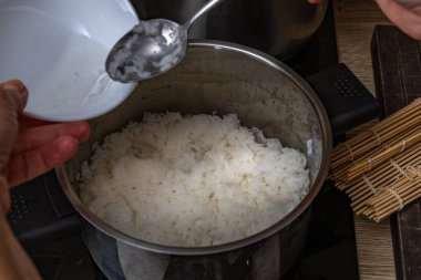 Pirinç kavanozuna pirinç sirkesi koymak, şeker, suşi malzemeleri, tencerede beyaz Çin pirinci, evde suşi yapmak, tipik Japon yemekleri için ev yapımı bir tarif.