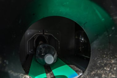 Kullanılmış plastik bir içecek şişesi şişe otomatındaki yuvaya yerleştirilmiş kullanılmış şişelerin iadesi, tek kullanımlık paketlerin geri dönüşümü, şişe koleksiyonu, tek kullanımlık şişelerin toplanması için hasarlı makine.