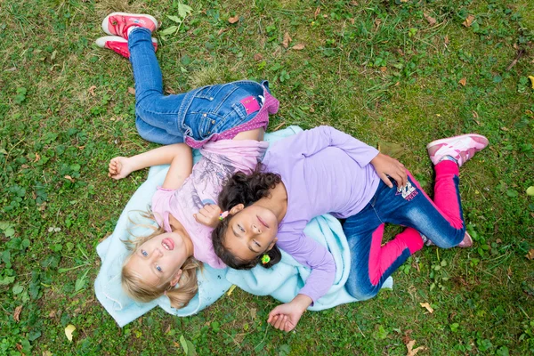 Två barn flickor låg i trädgården leende — Stockfoto