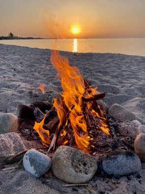 Gün batımında Issyk-Kul Gölü 'nün kumlu sahillerinde parlayan bir kamp ateşi. Yüksek kalite fotoğraf