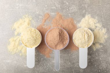 Protein powder. A spoonful of protein powder on a table. Different flavors of whey protein powder. Sports nutrition concept. Gym. Amino acid food supplement, creatine powder. Copy space.