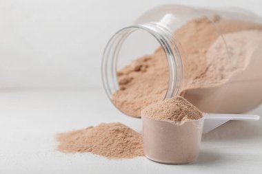 Protein powder. A spoonful of protein powder on a table. Different flavors of whey protein powder. Sports nutrition concept. Gym. Amino acid food supplement, creatine powder. Copy space.