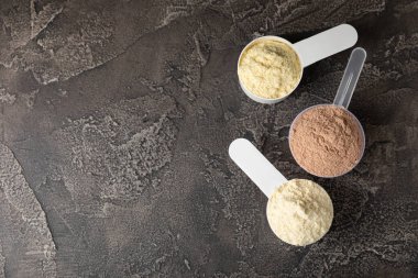 Protein powder. A spoonful of protein powder on a table. Different flavors of whey protein powder. Sports nutrition concept. Gym. Amino acid food supplement, creatine powder. Copy space.