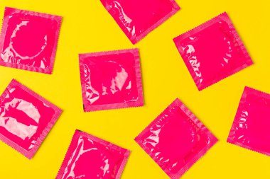 Renkli arka planda prezervatifler. Paketlemede renkli meyve temalı prezervatifler. Güvenli seks konsepti. Doğum kontrol hapı. Farklı doğum kontrol yöntemleri. AİDS önleme. Dünya AIDS Günü. Cinsel sağlık.