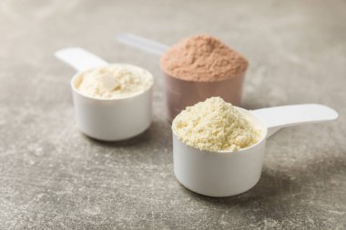 Protein powder. A spoonful of protein powder on a table. Different flavors of whey protein powder. Sports nutrition concept. Gym. Amino acid food supplement, creatine powder. Copy space.