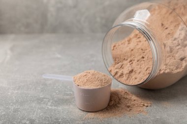 Protein powder. A spoonful of protein powder on a table. Different flavors of whey protein powder. Sports nutrition concept. Gym. Amino acid food supplement, creatine powder. Copy space.