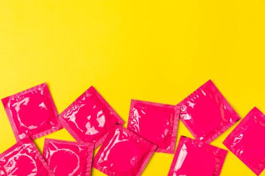 Renkli arka planda prezervatifler. Paketlemede renkli meyve temalı prezervatifler. Güvenli seks konsepti. Doğum kontrol hapı. Farklı doğum kontrol yöntemleri. AİDS önleme. Dünya AIDS Günü. Cinsel sağlık.