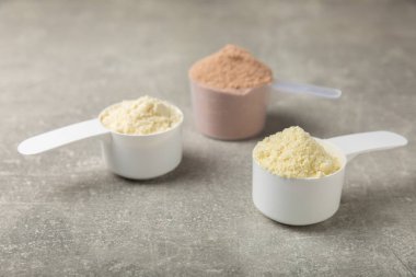 Protein powder. A spoonful of protein powder on a table. Different flavors of whey protein powder. Sports nutrition concept. Gym. Amino acid food supplement, creatine powder. Copy space.