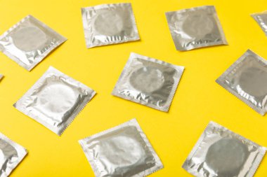 Renkli arka planda prezervatifler. Paketlemede renkli meyve temalı prezervatifler. Güvenli seks konsepti. Doğum kontrol hapı. Farklı doğum kontrol yöntemleri. AİDS önleme. Dünya AIDS Günü. Cinsel sağlık.