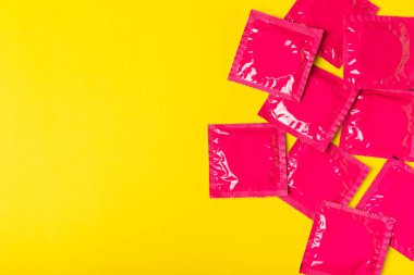 Renkli arka planda prezervatifler. Paketlemede renkli meyve temalı prezervatifler. Güvenli seks konsepti. Doğum kontrol hapı. Farklı doğum kontrol yöntemleri. AİDS önleme. Dünya AIDS Günü. Cinsel sağlık.