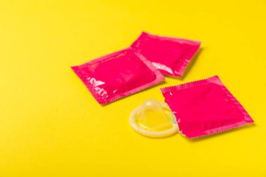 Renkli arka planda prezervatifler. Paketlemede renkli meyve temalı prezervatifler. Güvenli seks konsepti. Doğum kontrol hapı. Farklı doğum kontrol yöntemleri. AİDS önleme. Dünya AIDS Günü. Cinsel sağlık.