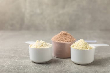 Protein powder. A spoonful of protein powder on a table. Different flavors of whey protein powder. Sports nutrition concept. Gym. Amino acid food supplement, creatine powder. Copy space.
