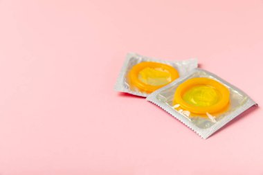 Renkli arka planda prezervatifler. Paketlemede renkli meyve temalı prezervatifler. Güvenli seks konsepti. Doğum kontrol hapı. Farklı doğum kontrol yöntemleri. AİDS önleme. Dünya AIDS Günü. Cinsel sağlık.