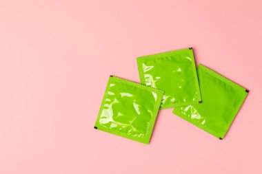 Renkli arka planda prezervatifler. Paketlemede renkli meyve temalı prezervatifler. Güvenli seks konsepti. Doğum kontrol hapı. Farklı doğum kontrol yöntemleri. AİDS önleme. Dünya AIDS Günü. Cinsel sağlık.