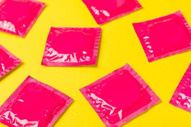 Renkli arka planda prezervatifler. Paketlemede renkli meyve temalı prezervatifler. Güvenli seks konsepti. Doğum kontrol hapı. Farklı doğum kontrol yöntemleri. AİDS önleme. Dünya AIDS Günü. Cinsel sağlık.