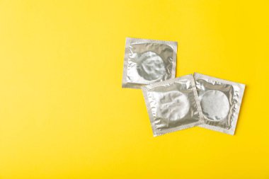 Renkli arka planda prezervatifler. Paketlemede renkli meyve temalı prezervatifler. Güvenli seks konsepti. Doğum kontrol hapı. Farklı doğum kontrol yöntemleri. AİDS önleme. Dünya AIDS Günü. Cinsel sağlık.