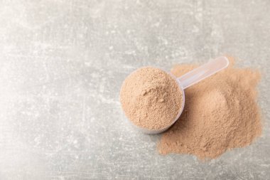 Protein powder. A spoonful of protein powder on a table. Different flavors of whey protein powder. Sports nutrition concept. Gym. Amino acid food supplement, creatine powder. Copy space.