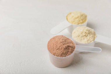 Protein powder. A spoonful of protein powder on a table. Different flavors of whey protein powder. Sports nutrition concept. Gym. Amino acid food supplement, creatine powder. Copy space.