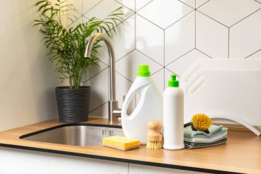 Mutfağın arka planında eko temizlik ürünleri var. Çevre dostu ev temizliği. Bir şişe doğal deterjan yüzeyi, eko fırçalar, süngerler ve paçavralar. Daha temiz bir kavram. Temizlik malzemeleri..