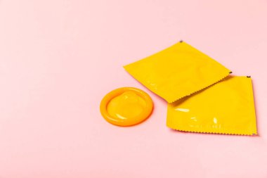 Renkli arka planda prezervatifler. Paketlemede renkli meyve temalı prezervatifler. Güvenli seks konsepti. Doğum kontrol hapı. Farklı doğum kontrol yöntemleri. AİDS önleme. Dünya AIDS Günü. Cinsel sağlık.