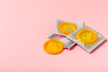 Renkli arka planda prezervatifler. Paketlemede renkli meyve temalı prezervatifler. Güvenli seks konsepti. Doğum kontrol hapı. Farklı doğum kontrol yöntemleri. AİDS önleme. Dünya AIDS Günü. Cinsel sağlık.