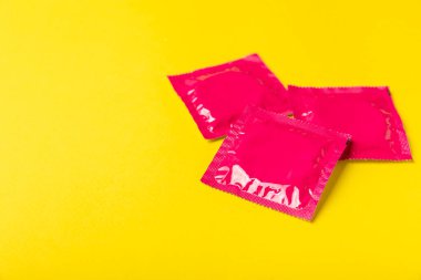 Renkli arka planda prezervatifler. Paketlemede renkli meyve temalı prezervatifler. Güvenli seks konsepti. Doğum kontrol hapı. Farklı doğum kontrol yöntemleri. AİDS önleme. Dünya AIDS Günü. Cinsel sağlık.