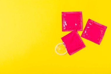 Renkli arka planda prezervatifler. Paketlemede renkli meyve temalı prezervatifler. Güvenli seks konsepti. Doğum kontrol hapı. Farklı doğum kontrol yöntemleri. AİDS önleme. Dünya AIDS Günü. Cinsel sağlık.