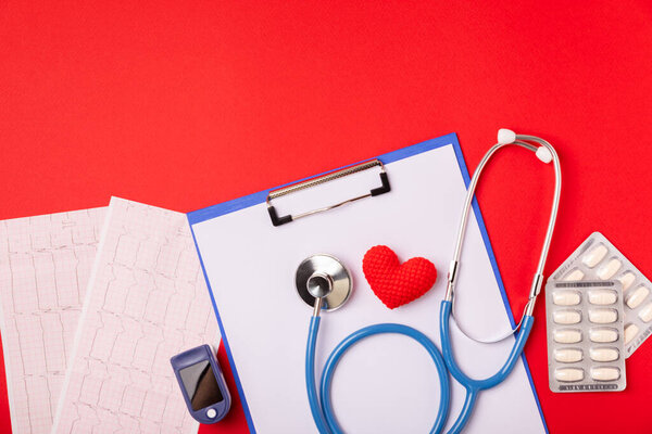 Медицинский стетоскоп, красное сердце и кардиограмма на цветном фоне. ЭКГ, сердечный приступ, сердечный приступ, кардиограмма. Следы пульса кардиограммы и концепция сердца. Healthcare.Space для текста