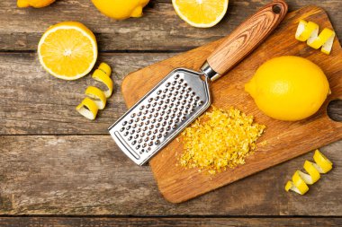 Limon aromalı. Taze sarı organik limonlar ve ahşap bir masada rende. Citrus lezzet rendesi. Limon kabuğu. Mesaj için C vitamini. Boşluğu kopyala.