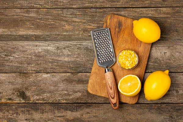 Limon aromalı. Taze sarı organik limonlar ve ahşap bir masada rende. Citrus lezzet rendesi. Limon kabuğu. Mesaj için C vitamini. Boşluğu kopyala.