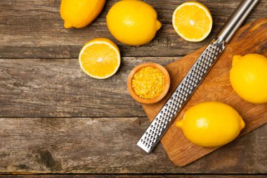 Limon aromalı. Taze sarı organik limonlar ve ahşap bir masada rende. Citrus lezzet rendesi. Limon kabuğu. Mesaj için C vitamini. Boşluğu kopyala.