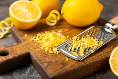 Limon aromalı. Taze sarı organik limonlar ve ahşap bir masada rende. Citrus lezzet rendesi. Limon kabuğu. Mesaj için C vitamini. Boşluğu kopyala.
