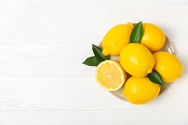 Tahta bir masada limon. Bir dilim taze limon. Turunçgil yapraklı taze limon. Limon suyu. Yemek ve içecek malzemeleri hazırlanıyor. Sağlıklı beslenme. Metin için C vitamini alanı.