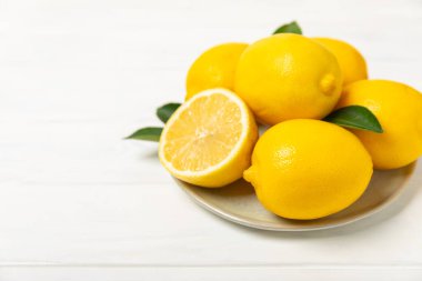 Tahta bir masada limon. Bir dilim taze limon. Turunçgil yapraklı taze limon. Limon suyu. Yemek ve içecek malzemeleri hazırlanıyor. Sağlıklı beslenme. Metin için C vitamini alanı.