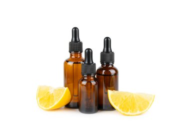 Limon dilimlenmiş limonlu bir şişede limon yağı ve beyaz arka planda izole edilmiş yapraklar. Limon yağı. Aromatik esanslı parfüm şişesi. Serum, limon özü. C vitamini. Doğal kozmetik ürünler. Aromaterapi. Spa mı? Metin için boşluk.