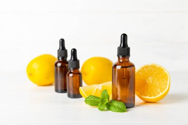Limon dilimlenmiş limonlu bir şişede limon yağı ve ahşap bir arka planda yapraklar. Limon yağı. Aromatik esanslı parfüm şişesi. Serum, limon özü. C vitamini. Doğal kozmetik ürünler. Aromaterapi. Spa mı? Metin için boşluk.
