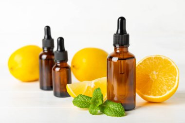 Limon dilimlenmiş limonlu bir şişede limon yağı ve ahşap bir arka planda yapraklar. Limon yağı. Aromatik esanslı parfüm şişesi. Serum, limon özü. C vitamini. Doğal kozmetik ürünler. Aromaterapi. Spa mı? Metin için boşluk.