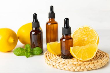 Limon dilimlenmiş limonlu bir şişede limon yağı ve ahşap bir arka planda yapraklar. Limon yağı. Aromatik esanslı parfüm şişesi. Serum, limon özü. C vitamini. Doğal kozmetik ürünler. Aromaterapi. Spa mı? Metin için boşluk.