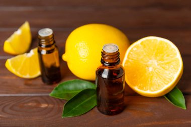 Limon dilimlenmiş limonlu bir şişede limon yağı ve ahşap bir arka planda yapraklar. Limon yağı. Aromatik esanslı parfüm şişesi. Serum, limon özü. C vitamini. Doğal kozmetik ürünler. Aromaterapi. Spa mı? Metin için boşluk.