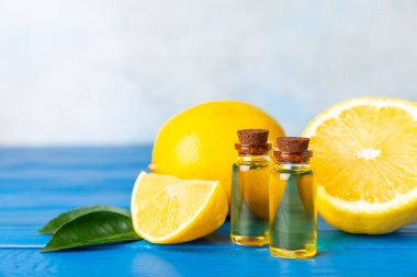 Limon dilimlenmiş limonlu bir şişede limon yağı ve ahşap bir arka planda yapraklar. Limon yağı. Aromatik esanslı parfüm şişesi. Serum, limon özü. C vitamini. Doğal kozmetik ürünler. Aromaterapi. Spa mı? Metin için boşluk.
