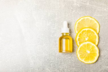 Limon dilimlenmiş limonlu bir şişede limon yağı ve ahşap bir arka planda yapraklar. Limon yağı. Aromatik esanslı parfüm şişesi. Serum, limon özü. C vitamini. Doğal kozmetik ürünler. Aromaterapi. Spa mı? Metin için boşluk.