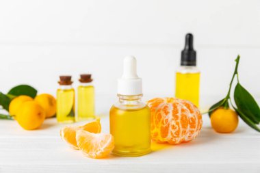 Tahta bir masada mandalina yağı. Bir şişe turunçgil yağı ve dilimlenmiş meyve. Mandalina kokulu mandalina yağı. Spa tedavileri için kozmetik yağı. Aromaterapi kavramı.